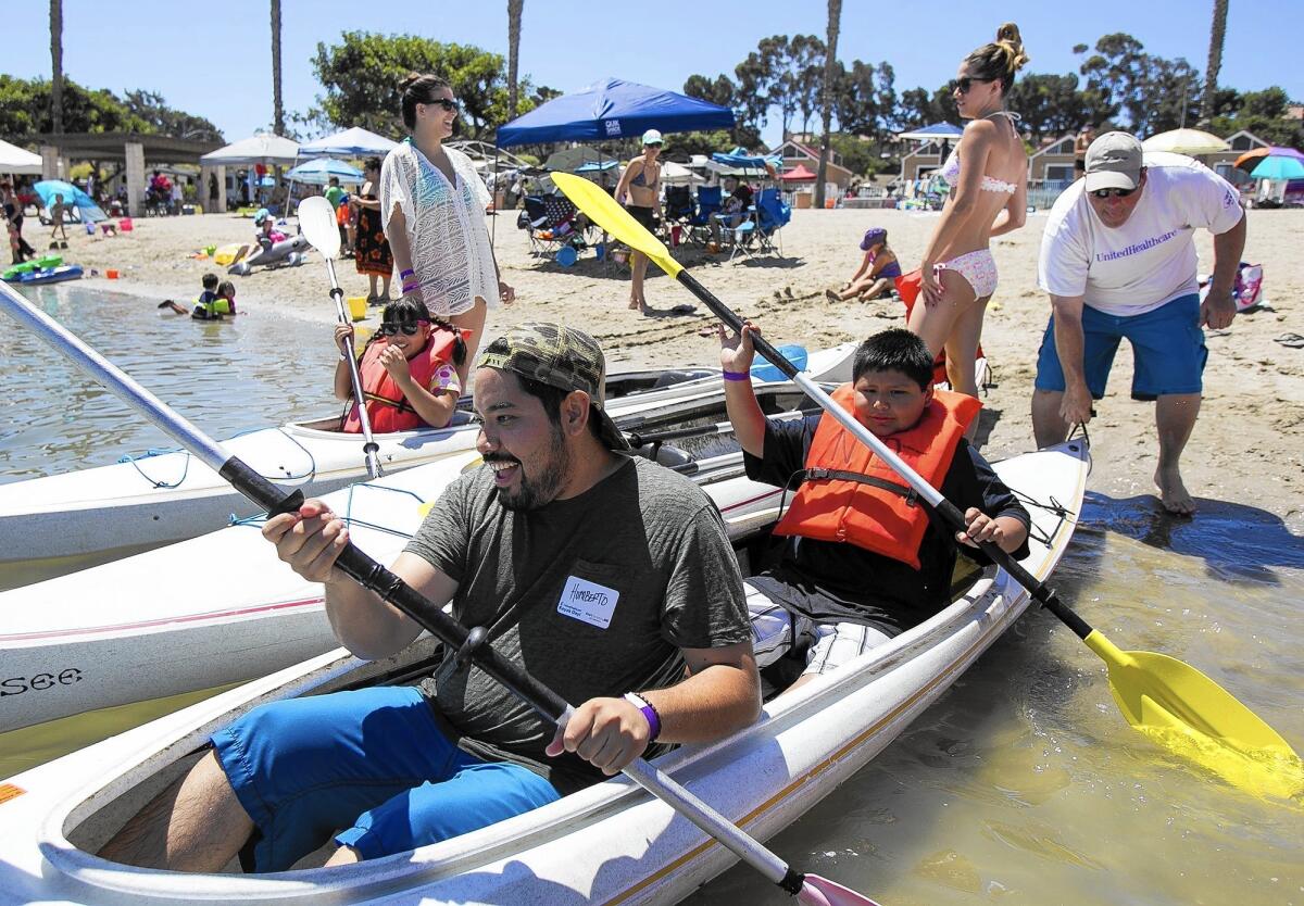 Humberto Rojas and Leo, 10, get a push from Lou Flocco during the Big F.U.N. Kayak Day presented by Big Brothers Big Sisters of Orange County and UnitedHealthcare at Newport Dunes on Saturday.