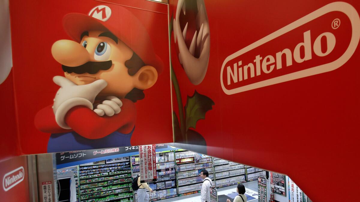 Shoppers walk under the logo of Nintendo and Super Mario Bros. characters at an electronics store in Tokyo in 2014.