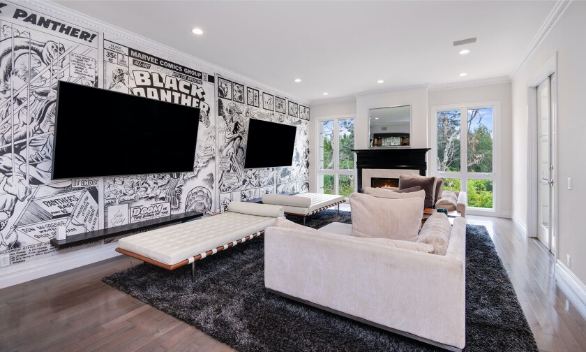 A room with couches, fireplace, video screens and a “Black Panther” comic-themed accent wall