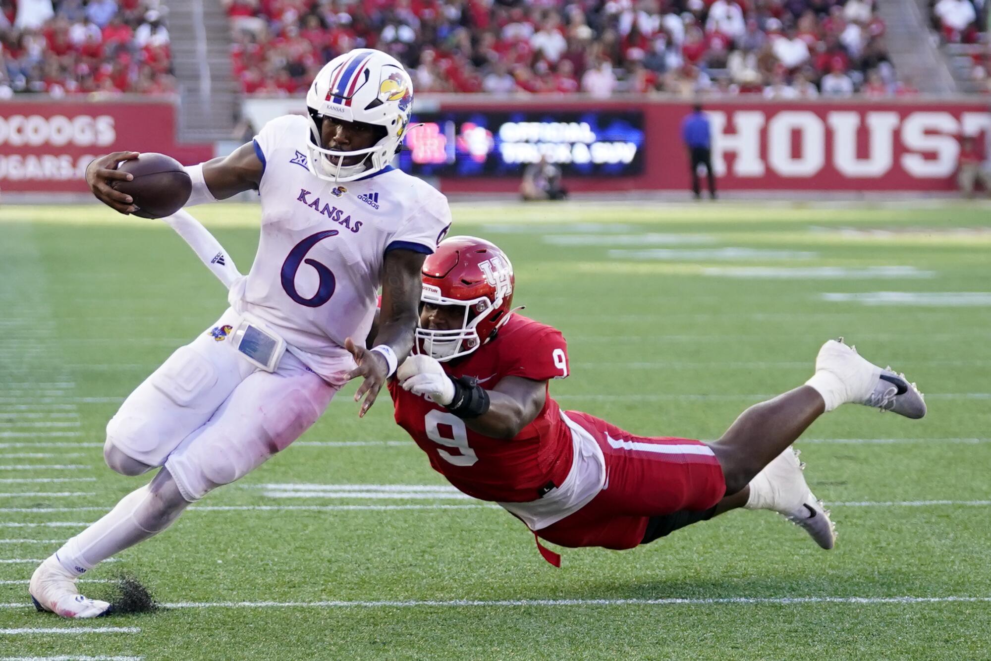 Kansas quarterback Jalon Daniels evades Houston defensive lineman Nelson Ceaser to score a touchdown.