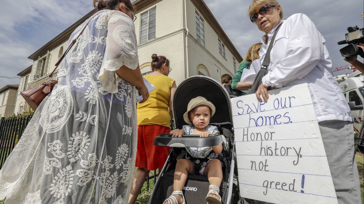Fifteen-month-old Zoey Moran, seated in a stroller next to her mother, Aura Valenzuela, left, watches as tenants of the Las Palmas Courtyard Apartments, the Coalition to Preserve L.A. and others gather for a news conference opposing the Crossroads Hollywood development.
