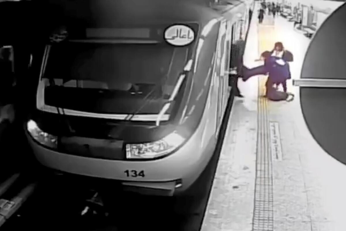 Women pull an injured girl from a train car onto a platform
