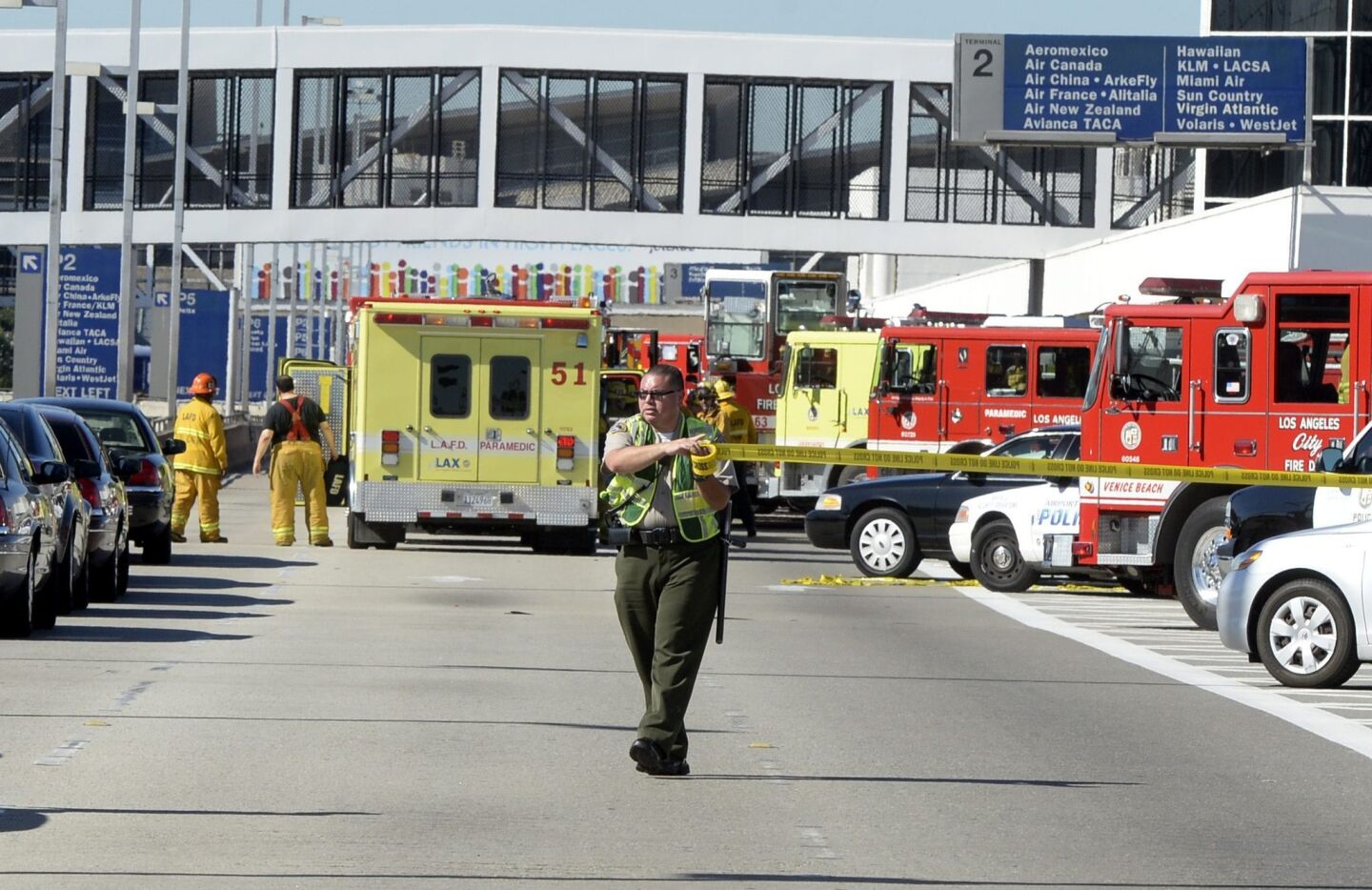 A police offer stretches crime scene tape across the road leading to Terminal 3 after Friday morning's shooting.