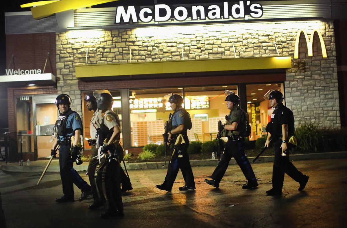 The unrest in Ferguson inspires a design analysis of American commercial strips. In this image, taken Tuesday evening, police watch demonstrators outside a McDonald's.
