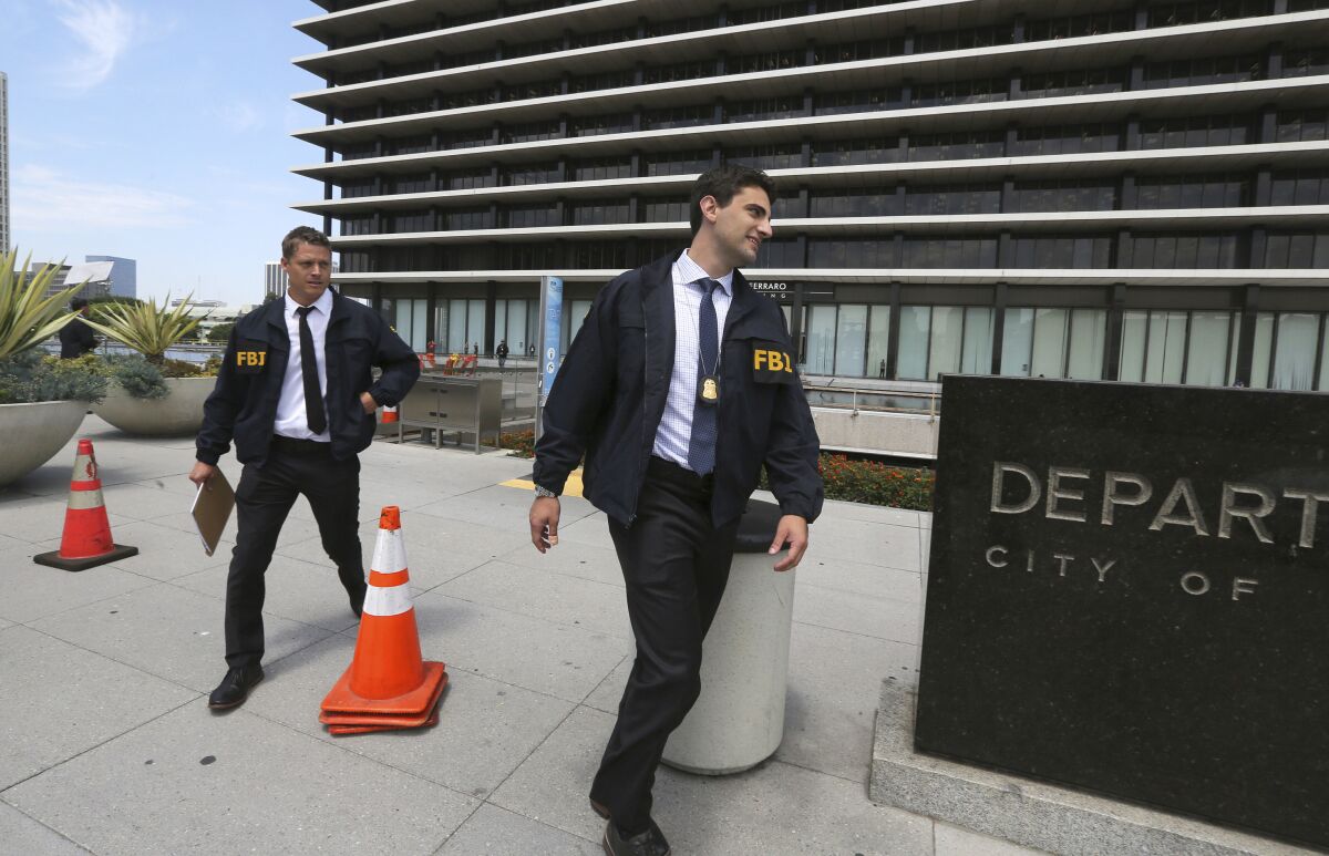 FILE - FBI agents leave the headquarters of the Los Angeles Department of Water and Power after spending several hours inside the building on July 22, 2019. David Wright, the former head of the Los Angeles Department of Water and Power, the nation's largest public utility, has agreed to plead guilty to taking bribes in a corruption scandal that grew out of an automated billing disaster that stuck ratepayers with exorbitant bills, federal prosecutors said Monday, Dec. 6, 2021. Los Angeles Mayor Eric Garcetti removed Wright from his job in 2019 after the FBI raided the water and power department and other city offices, months before his expected departure date. (AP Photo/Reed Saxon, File)