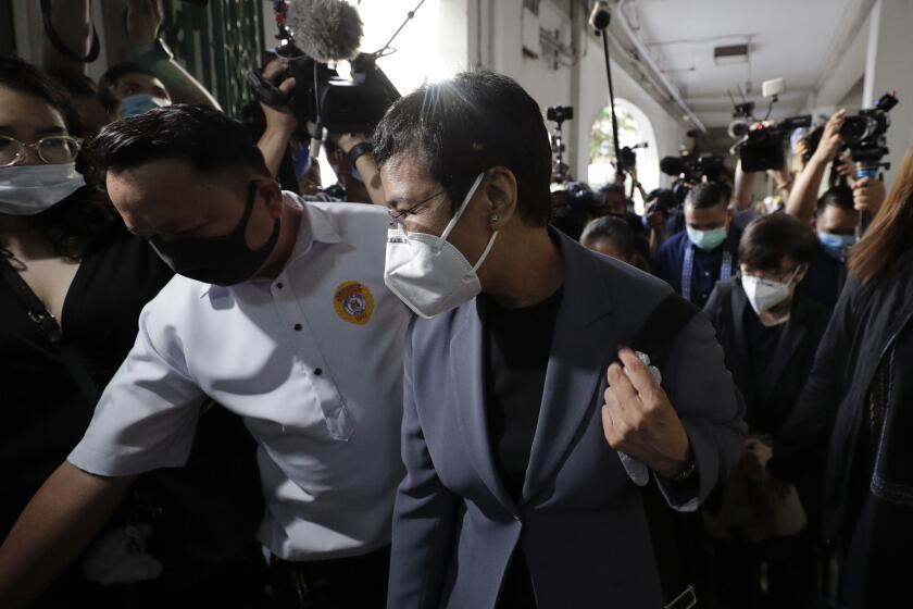 Rappler CEO and Executive Editor Maria Ressa, front right, wearing a protective mask, is escorted as she arrives to attend a court hearing at Manila Regional Trial Court, Philippines on Monday June 15, 2020. Ressa's verdict is expected to be announced Monday for a cyber libel case. (AP Photo/Aaron Favila)