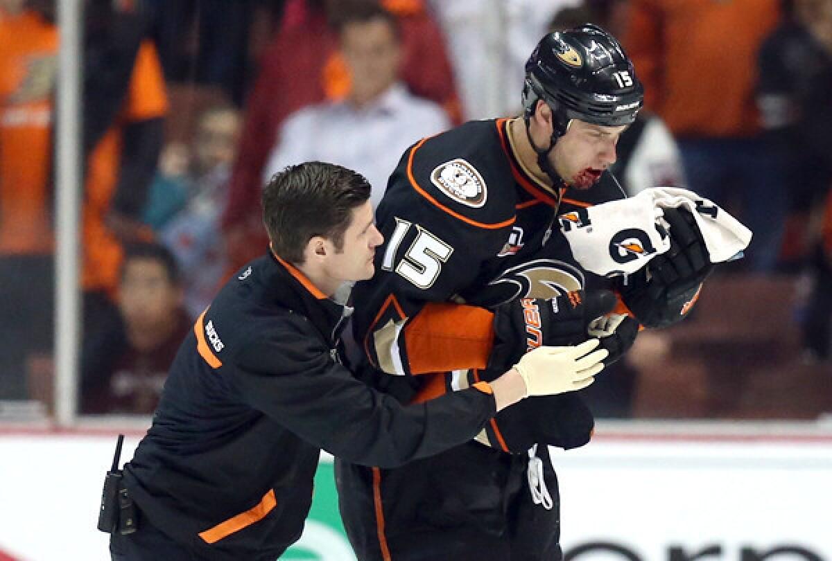 Ducks captain Ryan Getzlaf skates off the ice with a member of the medical staff after being hit in the face with a puck late in the third period against the Dallas Stars on Wednesday night at Honda Center.