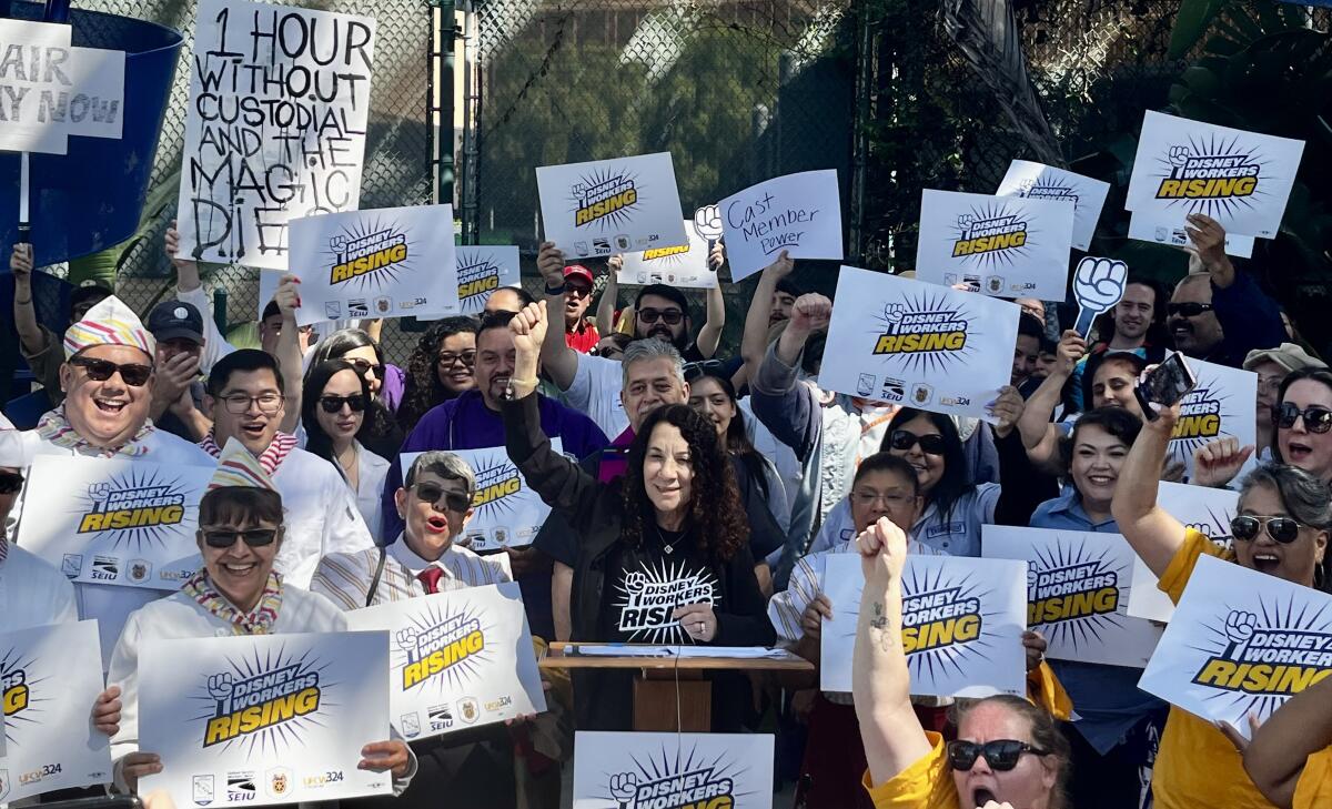 Disney union workers raise their fists up in demanding better pay from Orange County's largest employer