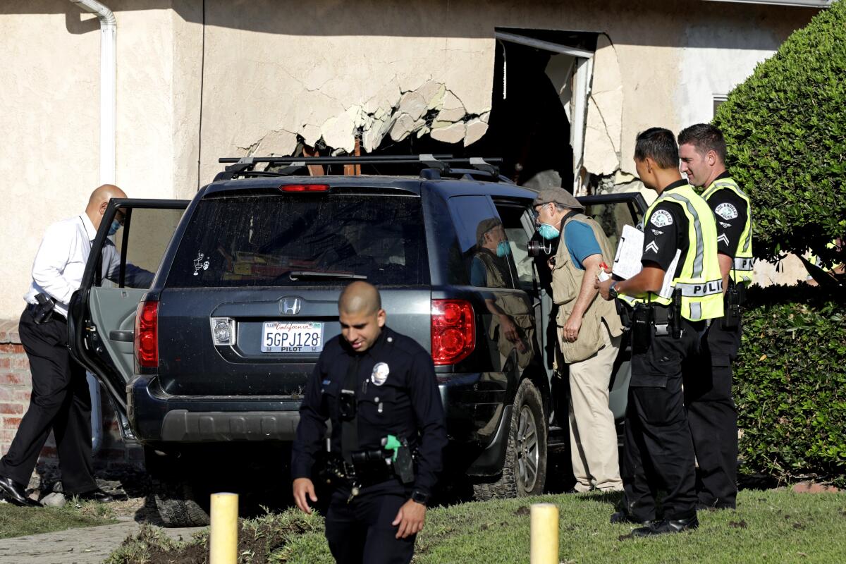 Police investigate the scene where an SUV crashed into a home