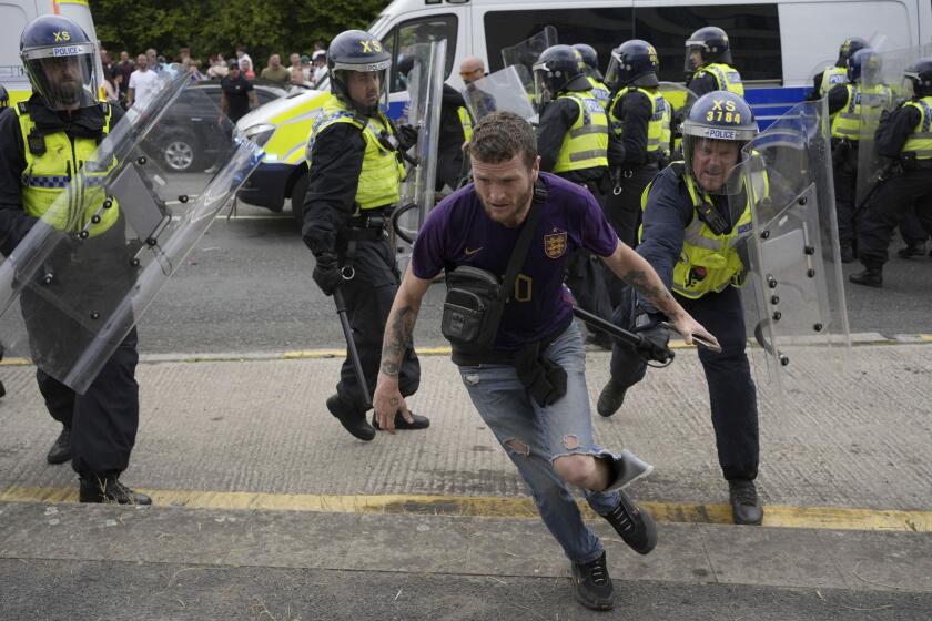 Police officers chase a protester as trouble flares during an anti-immigration protest outside the Holiday Inn Express in Rotherham, England, Sunday Aug. 4, 2024. (Danny Lawson/PA via AP)