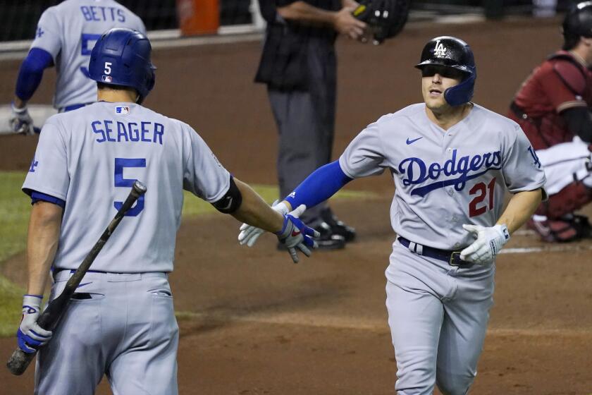 Los Angeles Dodgers' Enrique Hernandez, right, wearing Pittsburgh Pirates Hall of Fame player Roberto Clemente's No. 21 on Roberto Clemente Day, celebrates his home run against the Arizona Diamondbacks with Corey Seager (5) during the second inning of a baseball game Wednesday, Sept. 9, 2020, in Phoenix. (AP Photo/Ross D. Franklin)