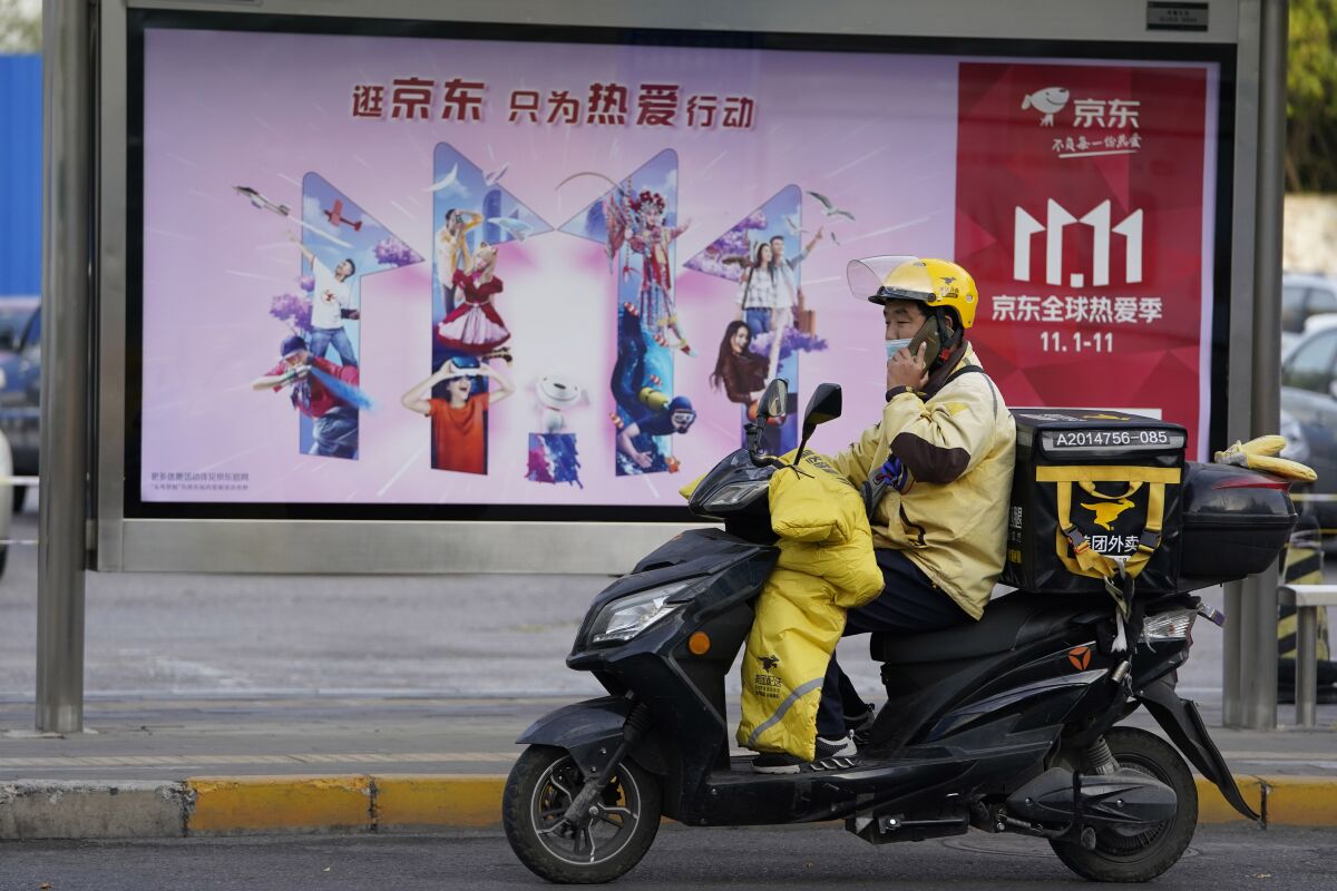 A delivery man passes by an ad for the Nov. 11 Sales Day in Beijing, China on Oct. 28, 2020. Chinese consumers are expected to spend tens of billions on everything from fresh food to luxury goods during this year's Singles' Day online shopping festival, as the country recovers from the coronavirus pandemic. (AP Photo/Ng Han Guan)