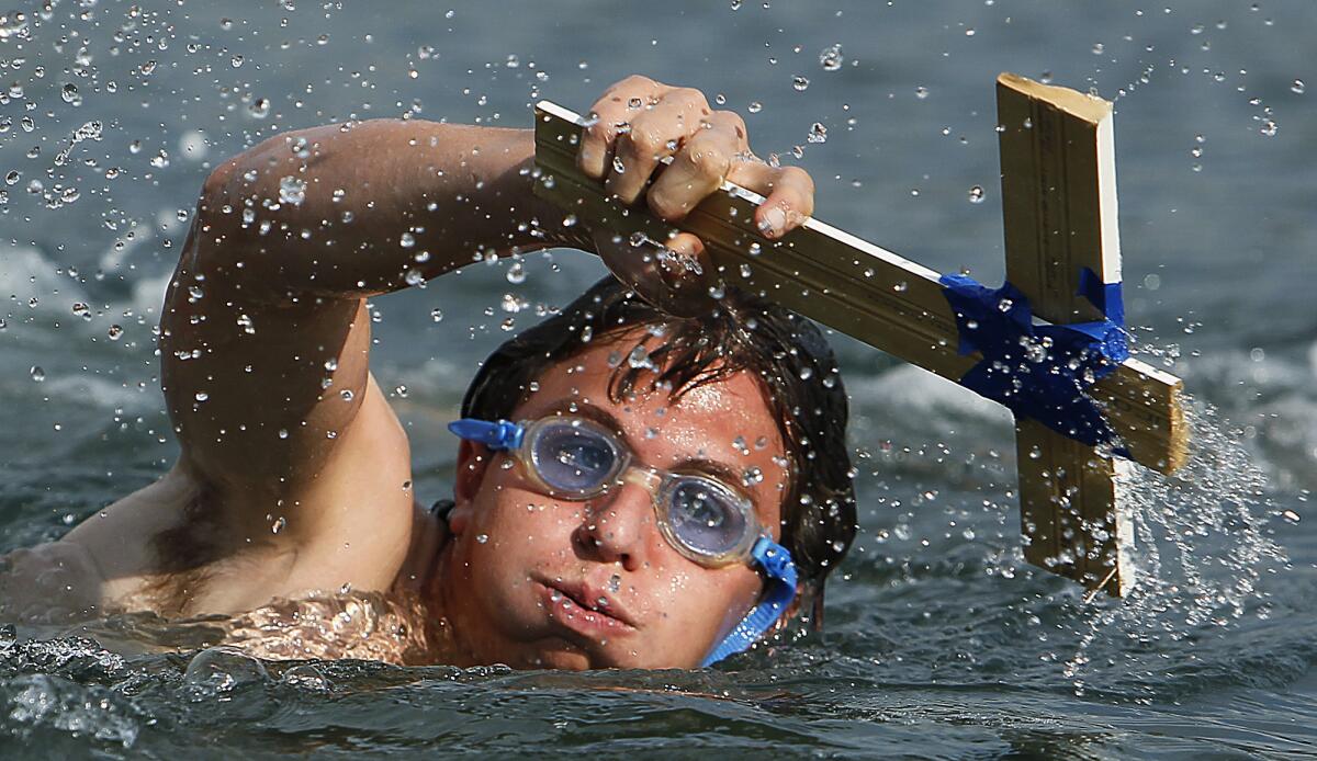 In the 2011 Epiphany celebration, Anthony Bussa, 16, swims with a cross after out-racing about a dozen other young swimmers to retrieve it.