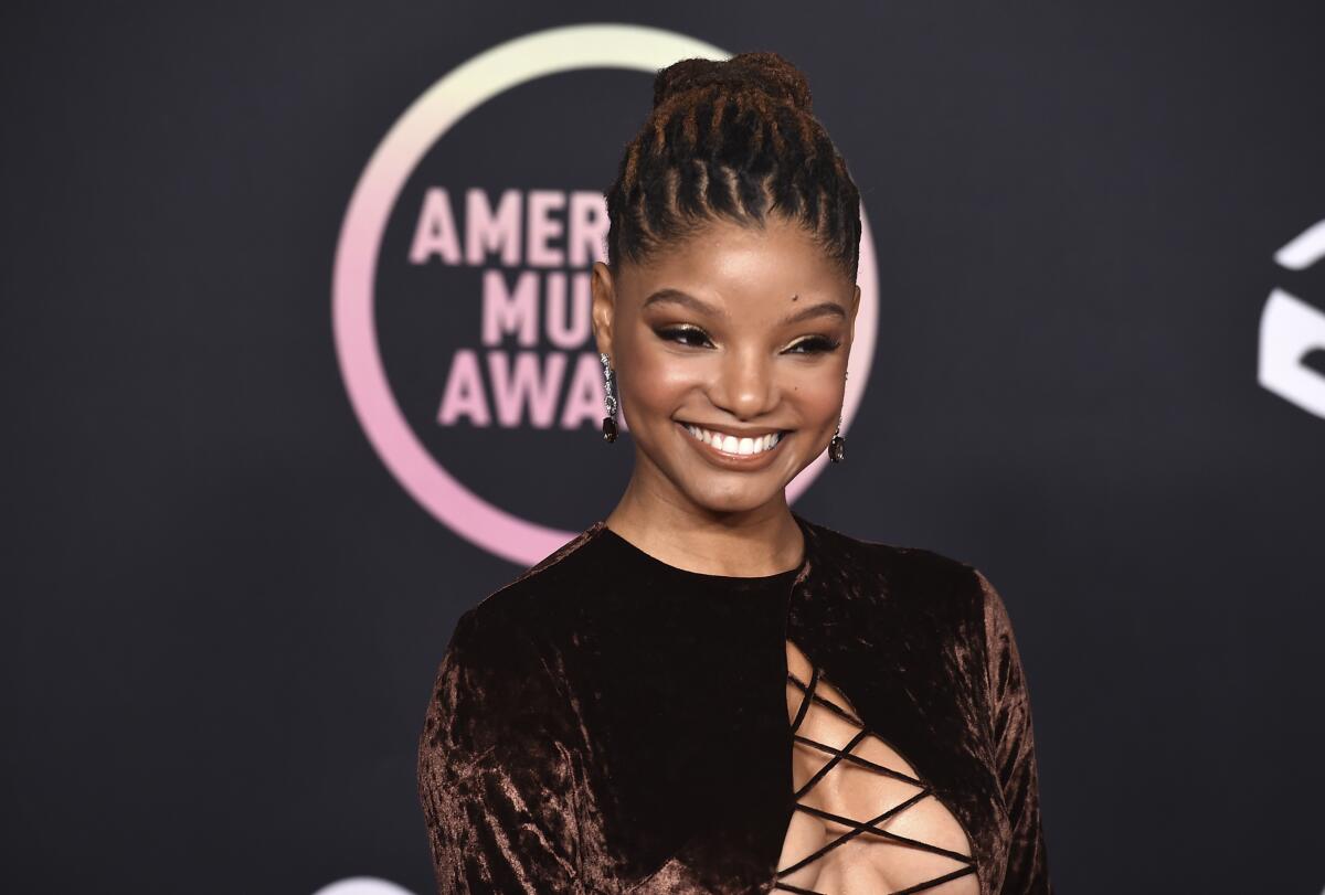 A woman with brown hair pulled back into a bun smiling in a brown velvet dress