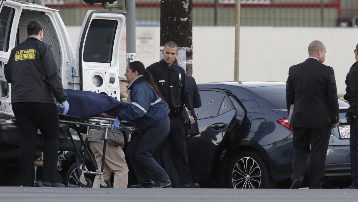 Los Angeles County coroner's investigators remove a man's body from a bullet-riddled car with an Uber sticker near the intersection of Griffin Avenue and North Broadway on Tuesday morning.