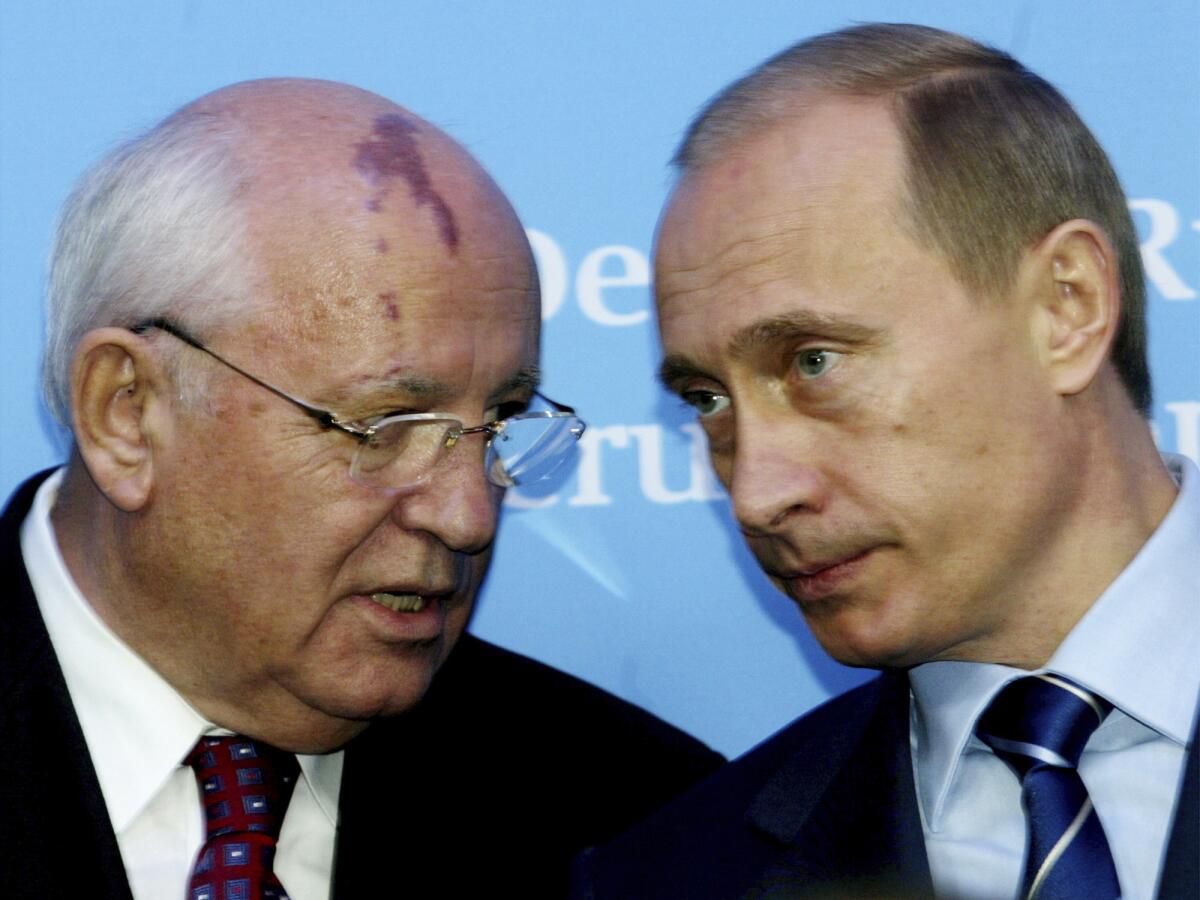 Vladimir Putin, right, leans in to listen to Mikhail Gorbachev 