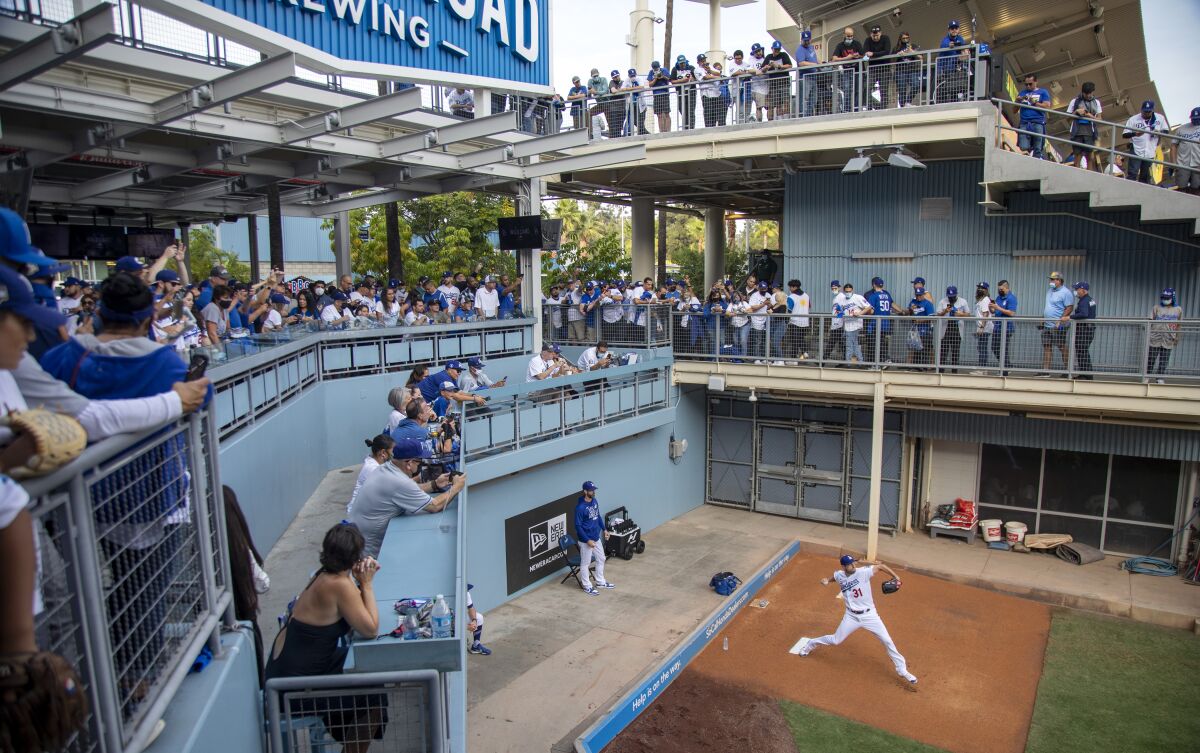 Fans watch Dodgers starting pitcher Max Scherzer warm up in the bullpen.