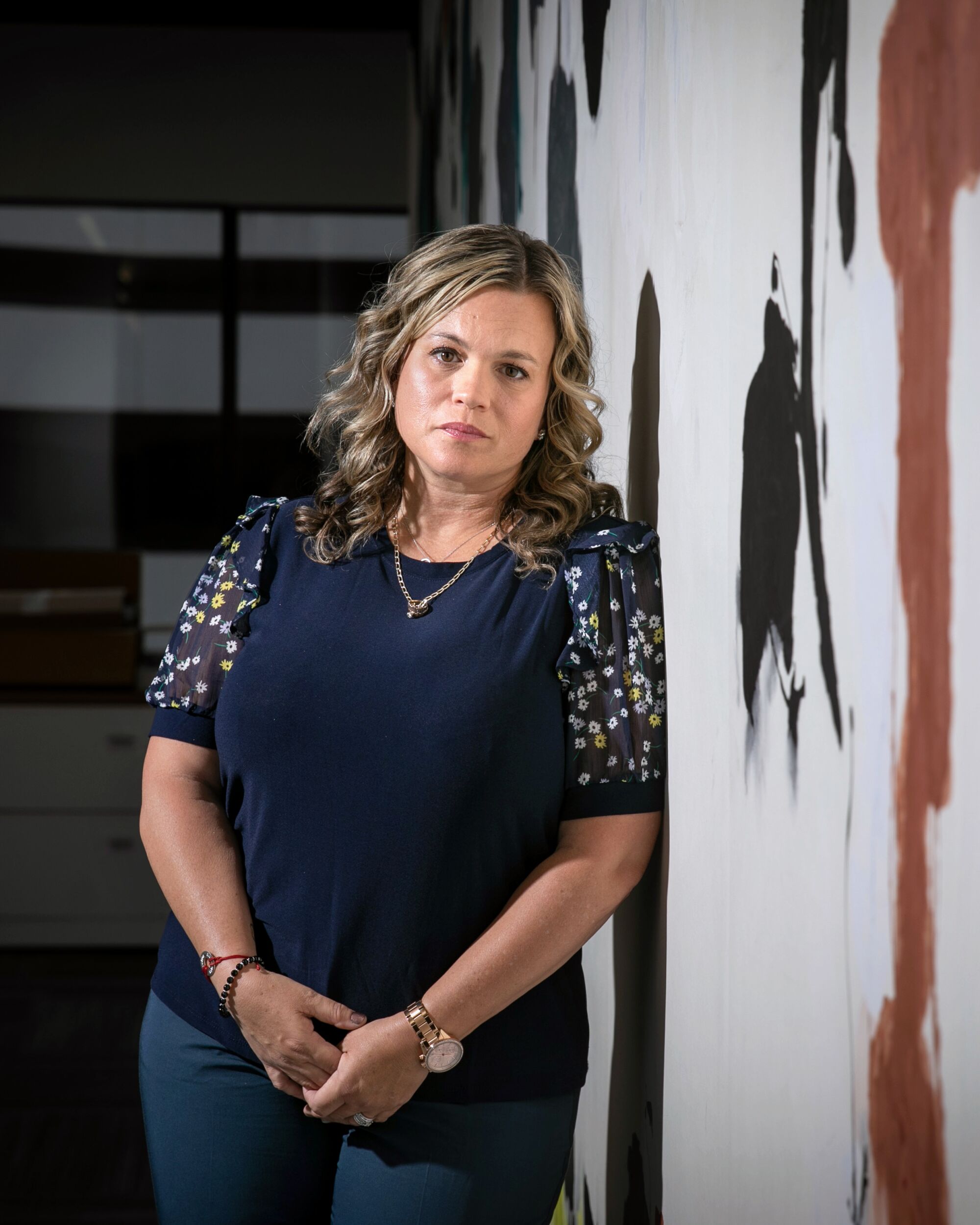 A vertical frame of a waist-up portrait of Mychelle Blandin looking at the camera