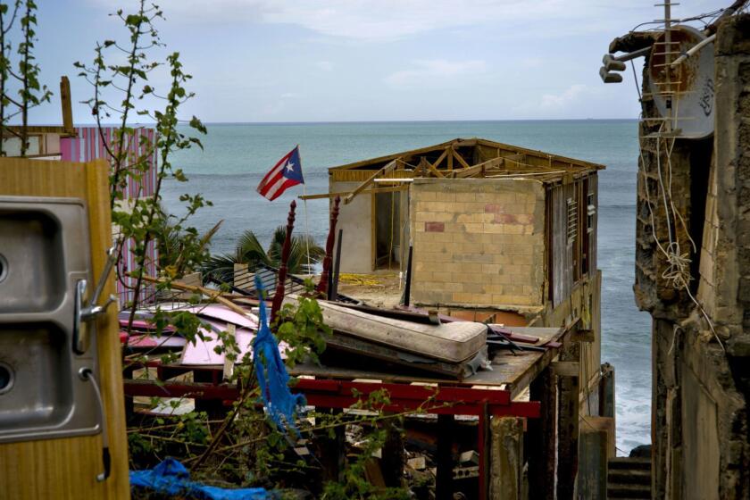 FILE - In this Oct. 5, 2017 file photo, a Puerto Rican national flag is mounted on debris of a damaged home in the aftermath of Hurricane Maria in the seaside slum La Perla, San Juan, Puerto Rico. An independent investigation ordered by Puerto Rico???s government estimates that nearly 3,000 people died as a result of Hurricane Maria. The findings issued Tuesday, Aug. 28, 2018, by the Milken Institute School of Public Health at George Washington University contrast sharply with the official death toll of 64. (AP Photo/Ramon Espinosa)