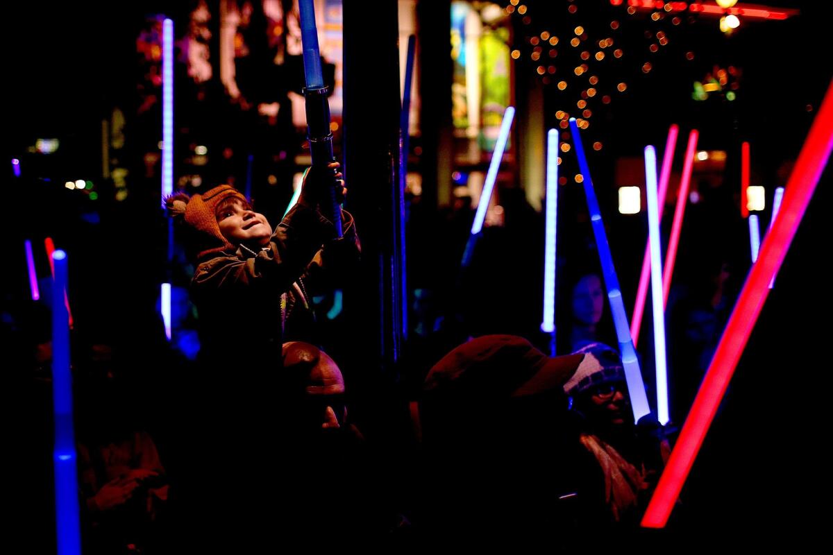 Jay Cotton Jr., 4, of Whittier, sits on his father Jay Cotton's shoulders during a lightsaber vigil for "Star Wars" actress Carrie Fisher held in Downtown Disney.