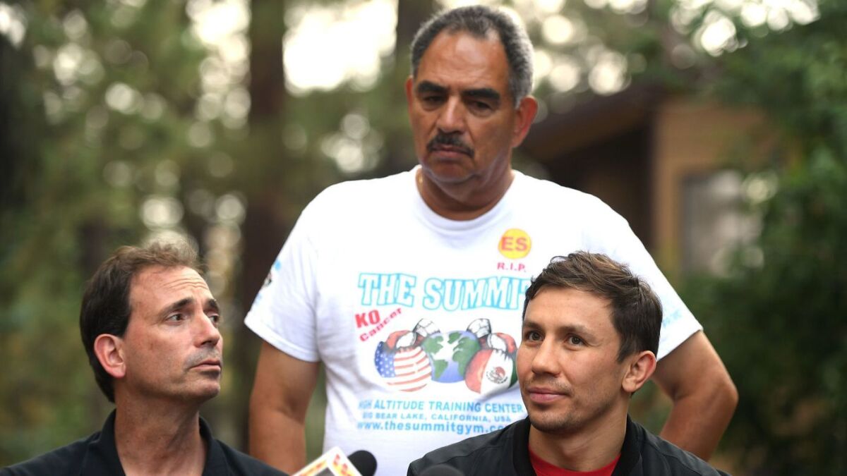 Trainer Abel Sanchez stands as Gennady Golovkin, right, speaks to the media alongside promoter Tom Loeffler.