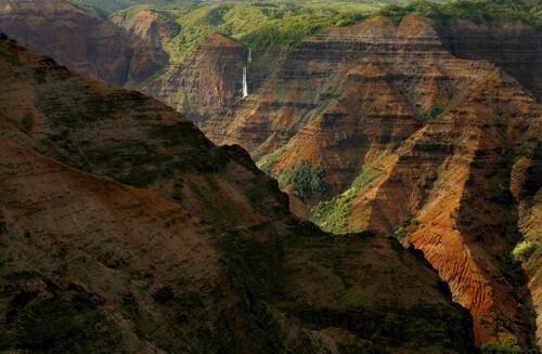 Glowing in the light of a setting sun, the red-colored walls of Waimea Canyon in Kauai as seen from the Canyon Lookout.