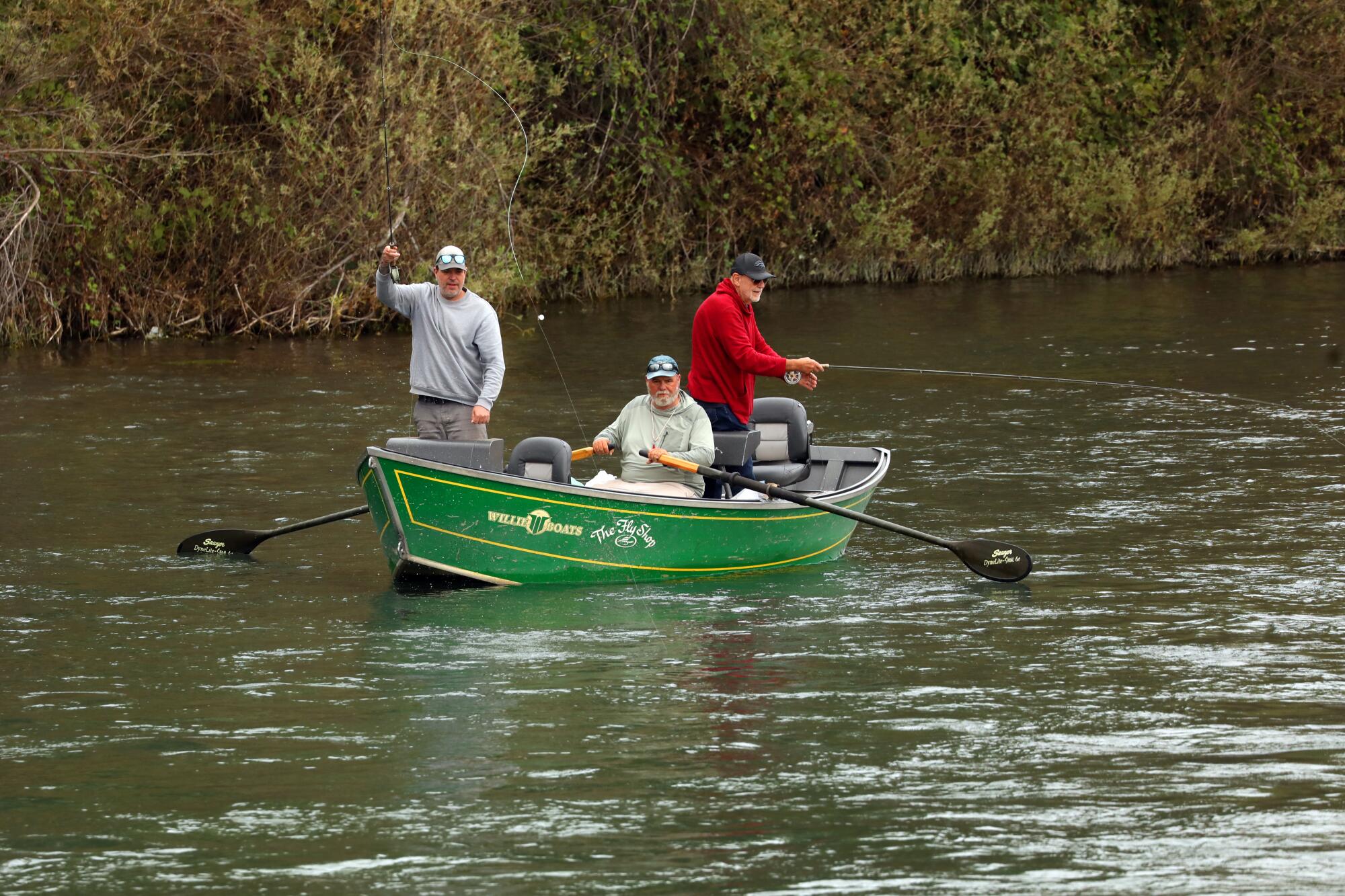 Three people fish from a rowboat in the Sacramento River. 
