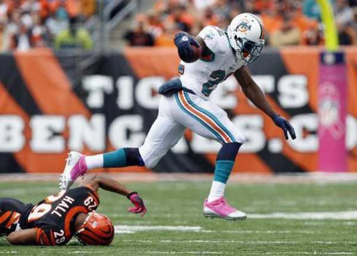 The Miami Dolphins' Reggie Bush runs the ball by the Cincinnati Bengals.