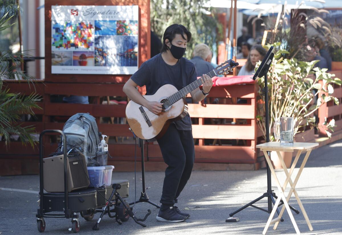 A street performer plays and sings on the Promenade on Forest in Laguna Beach in 2020.