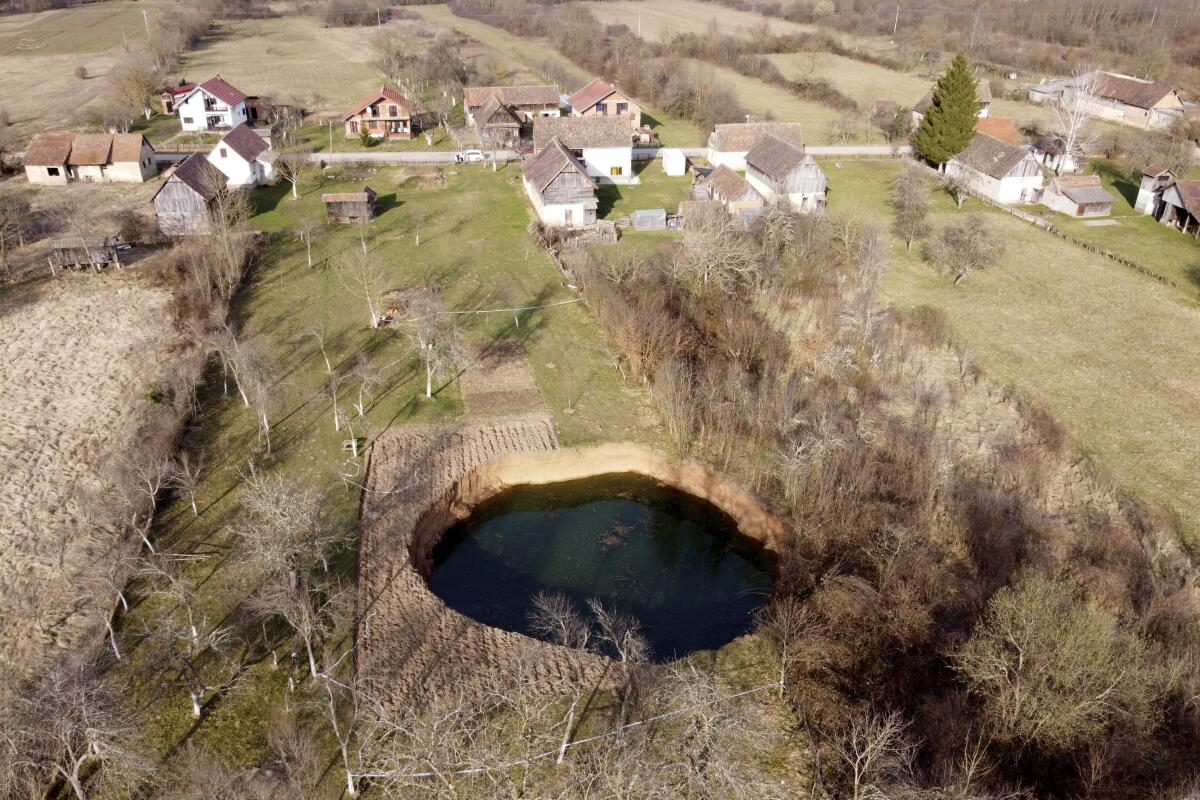 This aerial photo shows a sinkhole in the village of Mececani, central Croatia, Thursday, March 4, 2021. A central Croatian region about 40 kilometers (25 miles) southwest of the capital Zagreb is pocked with round holes of all sizes, which appeared after December's 6.4-magnitude quake that killed seven people and caused widespread destruction. Scientists have been flocking to Mecencani and other villages in the sparsely-inhabited region for observation and study. (AP Photo/Darko Bandic)
