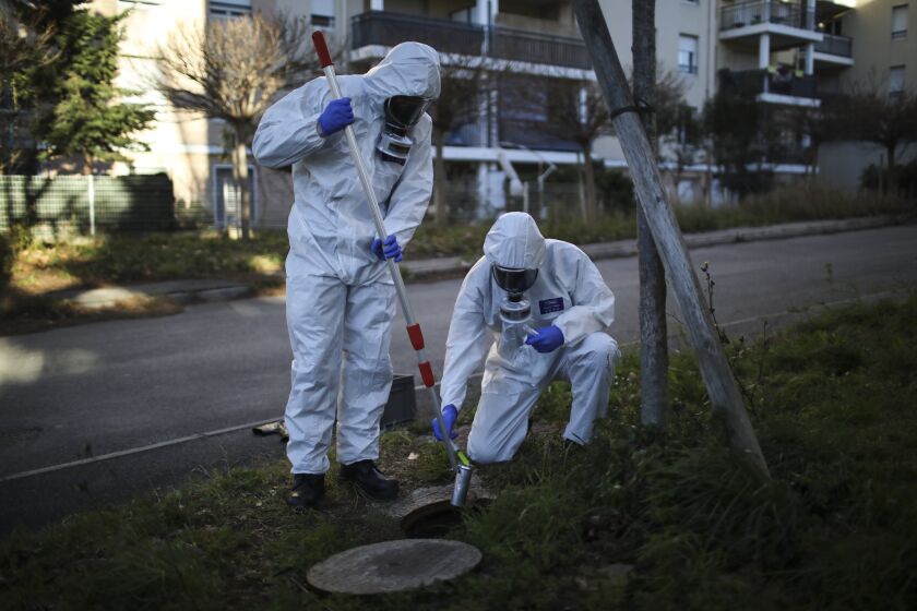 FILE - Firefighters from the Marins-Pompiers of Marseille extract samples of sewage water at a retirement home in Marseille, southern France, Thursday Jan. 14, 2021, to trace concentrations of COVID-19 and the highly contagious variant that has been discovered in Britain. As coronavirus infections rise in some parts of the world, experts are watching for a potential new COVID-19 surge in the U.S. — and wondering how long it will take to detect. (AP Photo/Daniel Cole)