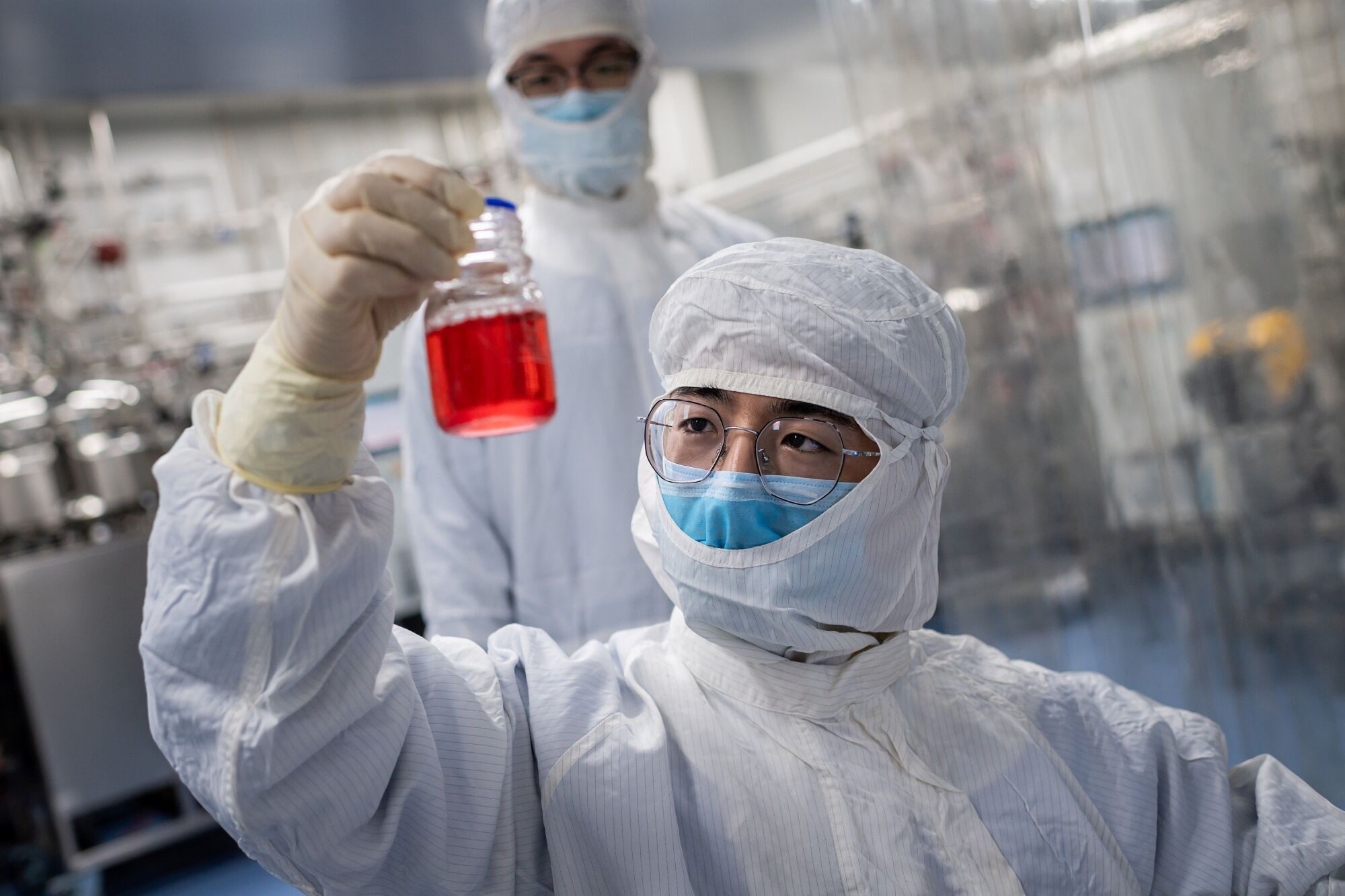 An engineer at Sinovac Biotech in Beijing looks at monkey kidney cells as he tests an experimental COVID-19 vaccine.