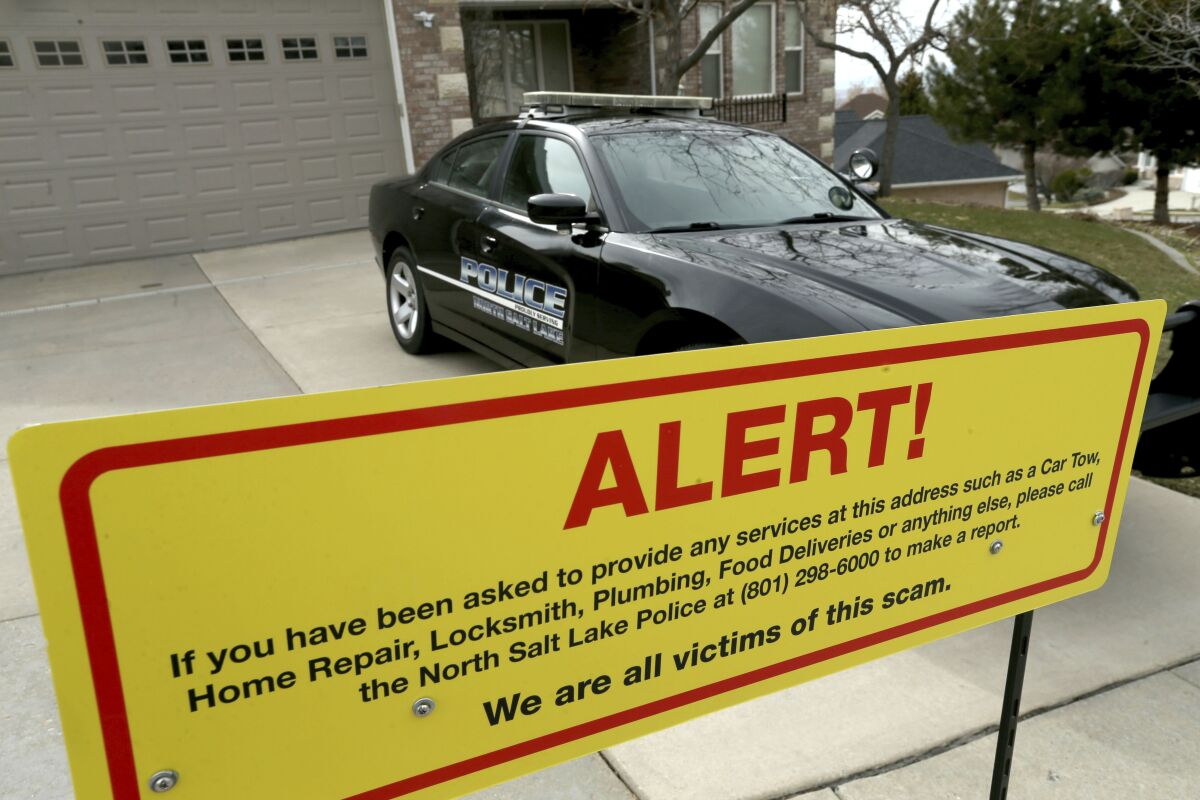 FILE - This March 21, 2019, file photo shows a warning sign and a police officer's vehicle at Walt Gilmore's home in North Salt Lake, Utah. A Hawaii man who pleaded guilty to cyberstalking the Utah family by sending more than 500 people to their house for unwanted services including food deliveries, plumbers and prostitutes was sentenced Thursday, May 13, 2021, to three years of supervision and ordered to adhere to strict limitations on use of the internet. (Laura Seitz/The Deseret News via AP, File)