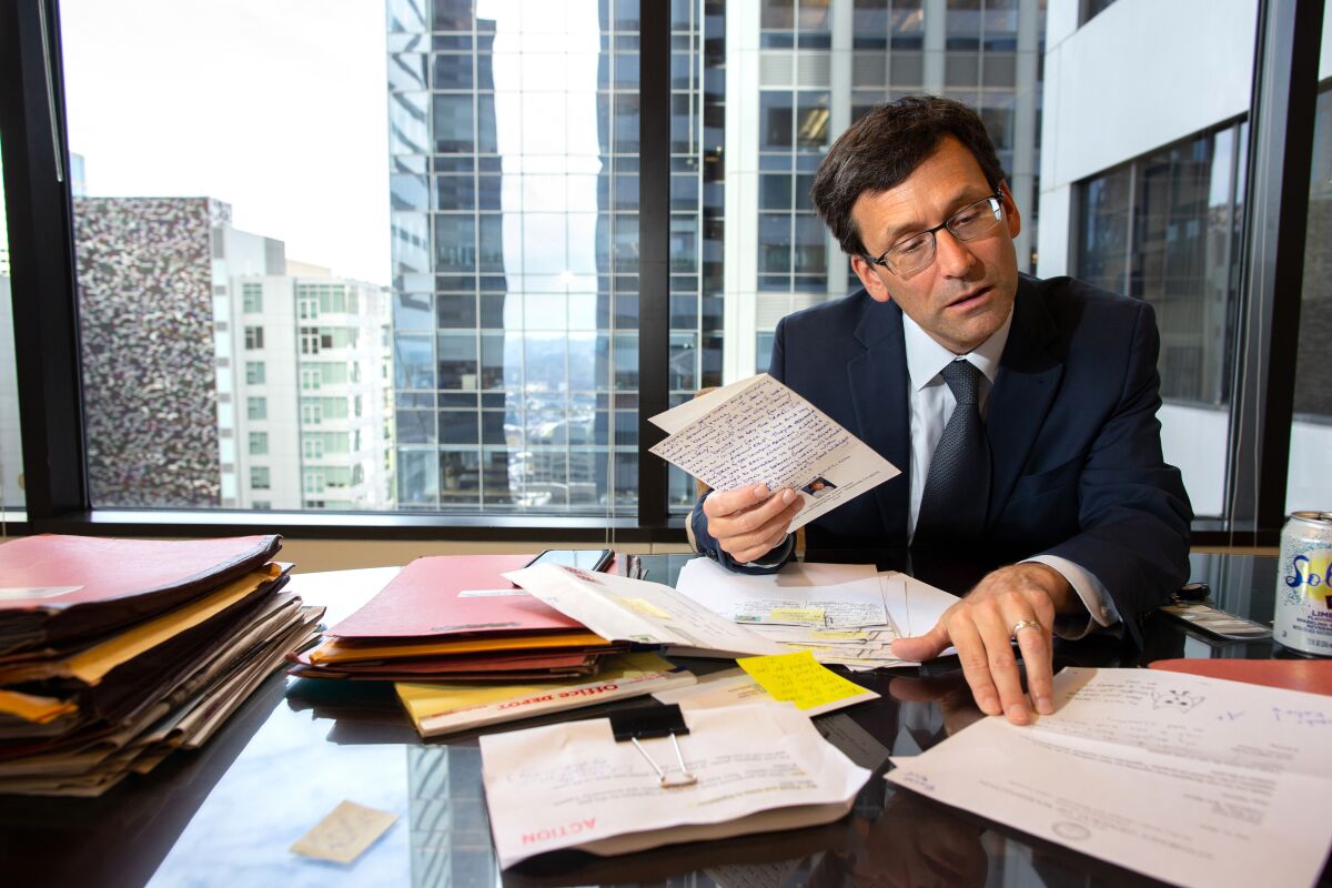 Ferguson, shown in his Seattle office on Sept. 19, leafs through letters that he's received concerning his lawsuits against the Trump administration. 