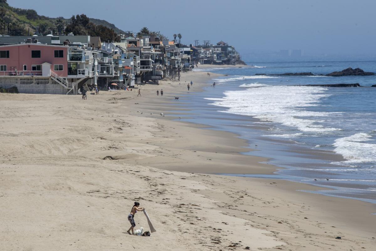 MALIBU, CA - APRIL 23: A woman sets out her towel for sunbathing at Dan Blocker Beach on Thursday, April 23, 2020 in Malibu, CA. To fend off coronavirus contagion, Los Angeles County has kept beaches closed, but hundreds of beachgoers flaunted the rules up and down the coastline from Santa Monica to Malibu. (Brian van der Brug / Los Angeles Times)