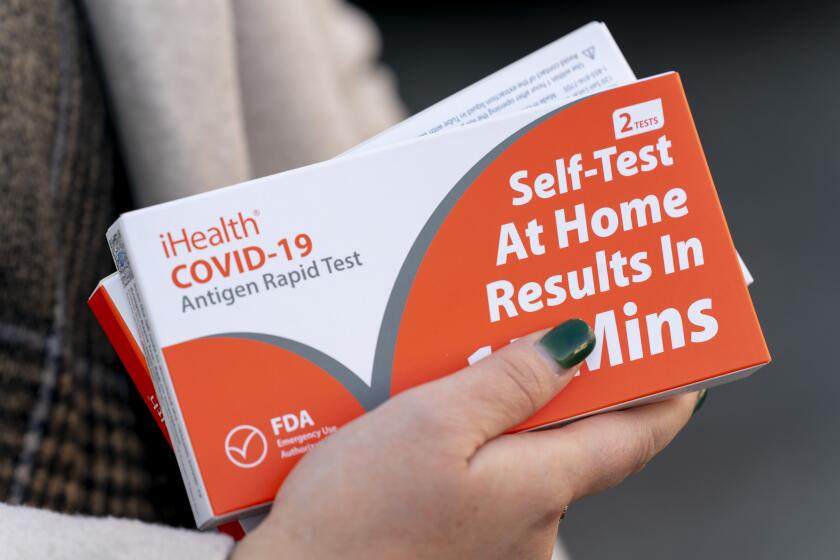 FILE - A woman holds two boxes of at-home Covid-19 test kits in Washington, Dec. 22, 2021. (AP Photo/Andrew Harnik, File)