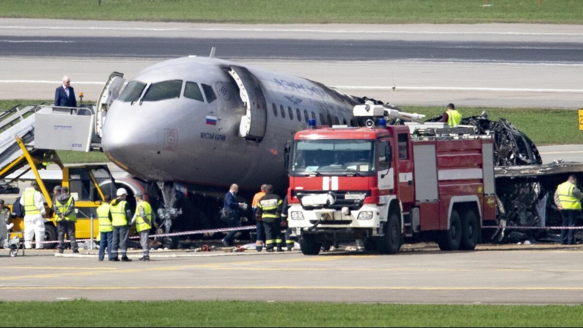 People gather around the damaged Aeroflot plane just outside Moscow. Some passengers reportedly slowed the exit process by taking luggage with them.