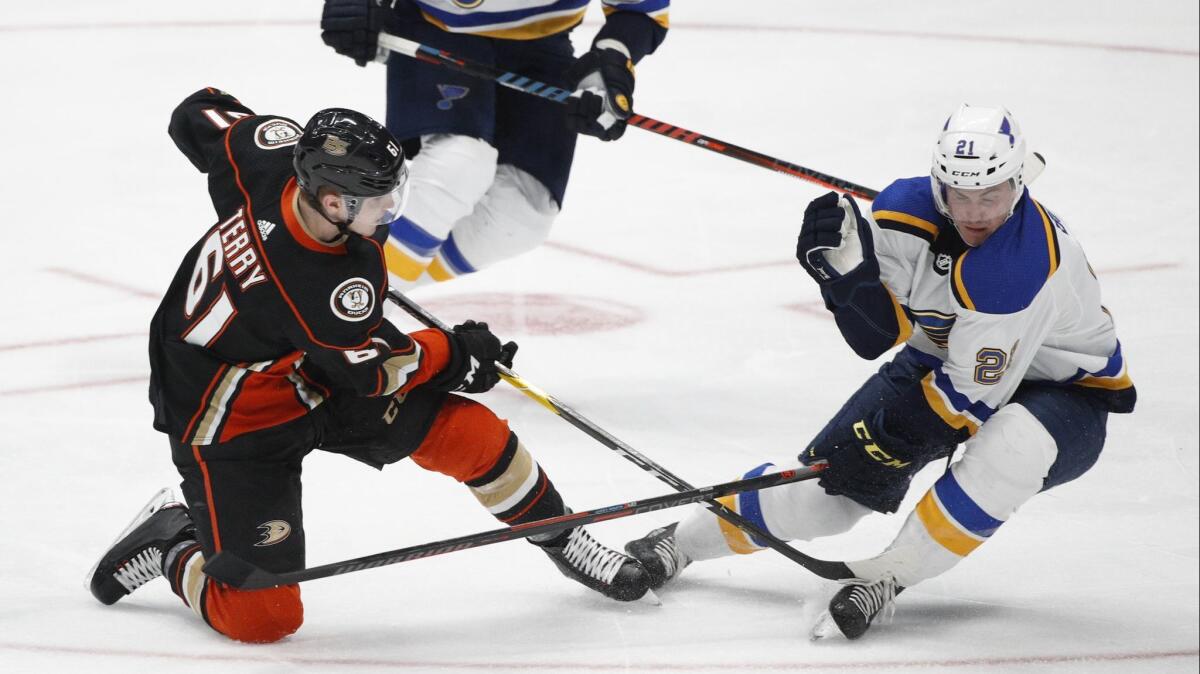 Ducks' Troy Terry, left, shoots under defense by St. Louis Blues' Tyler Bozak during the third period.
