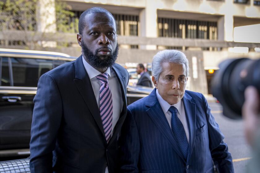 Prakazrel “Pras” Michel and his defense lawyer David Kenner walking out of black SUV, both wearing dark blue suits