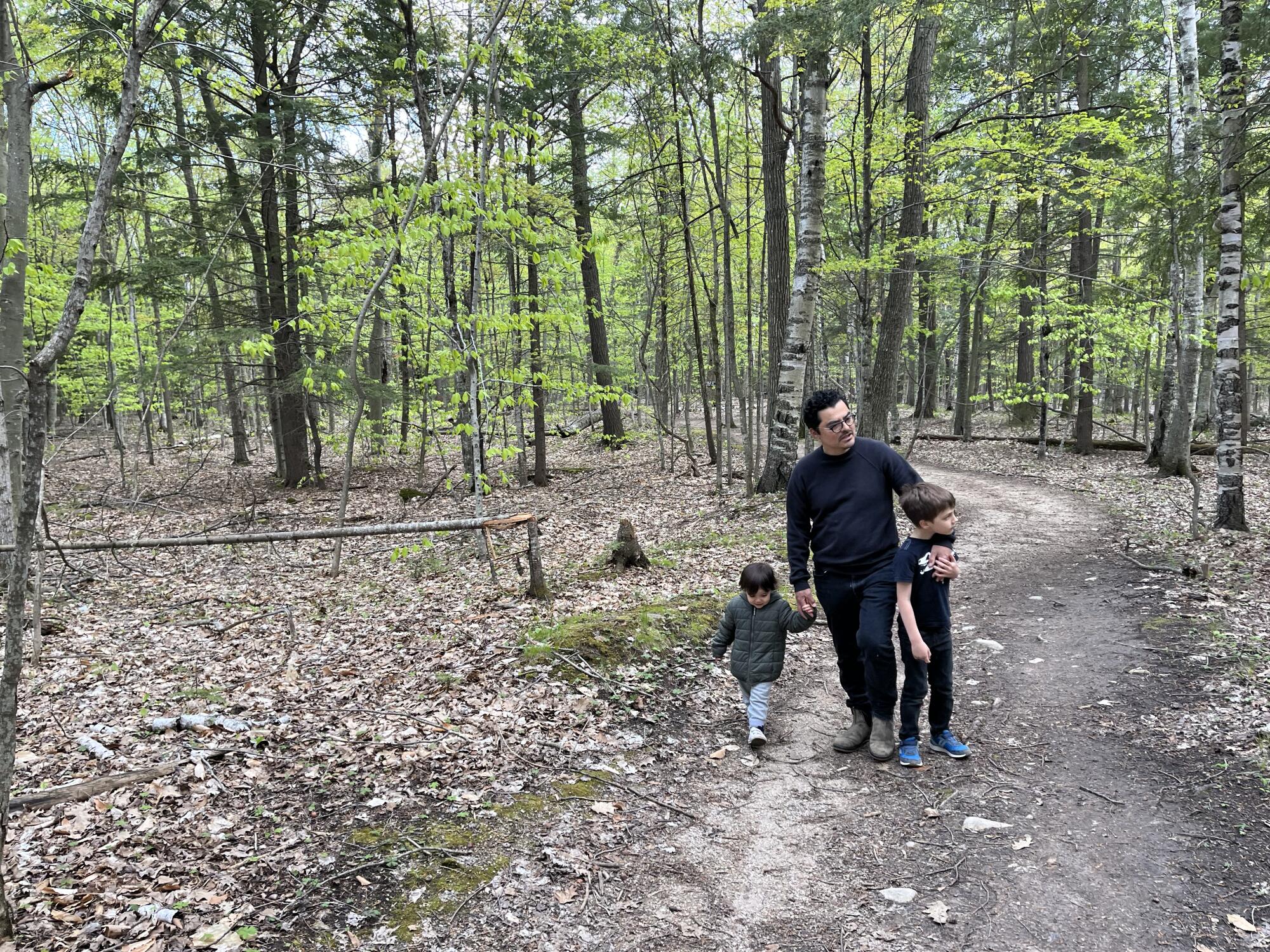 Carlos Salgado walks outdoors with two children.