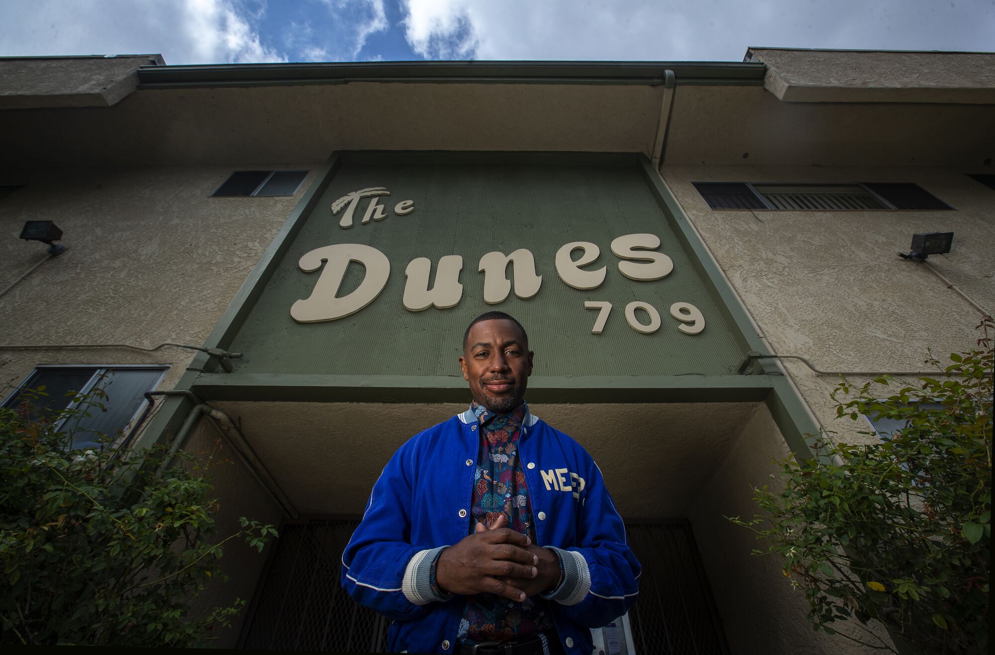 A man stands in front of a sign that says the Dunes.