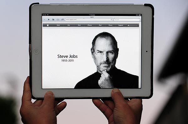 The Apple website's home page, paying homage to Steve Jobs, is displayed on an iPad 2.