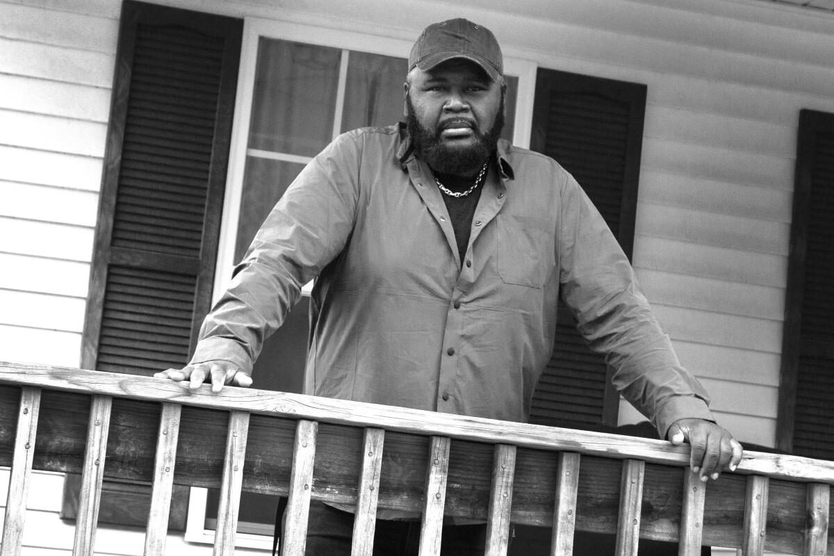 A man with his hands on porch railing