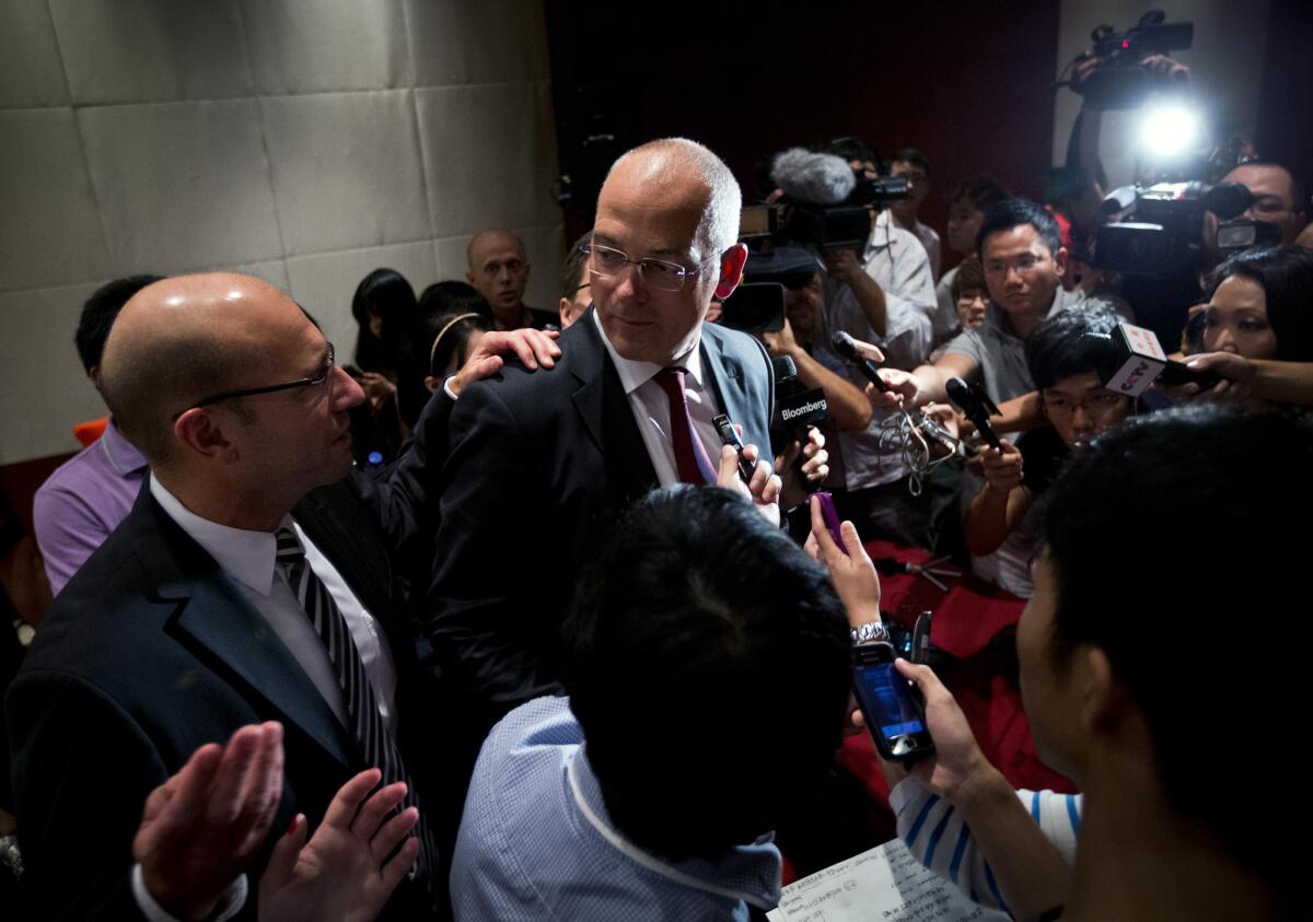 Theo Spierings, center, chief executive of New Zealand dairy giant Fonterra, is surrounded by journalists at a news conference in Beijing where he apologized for a tainted-milk scare.