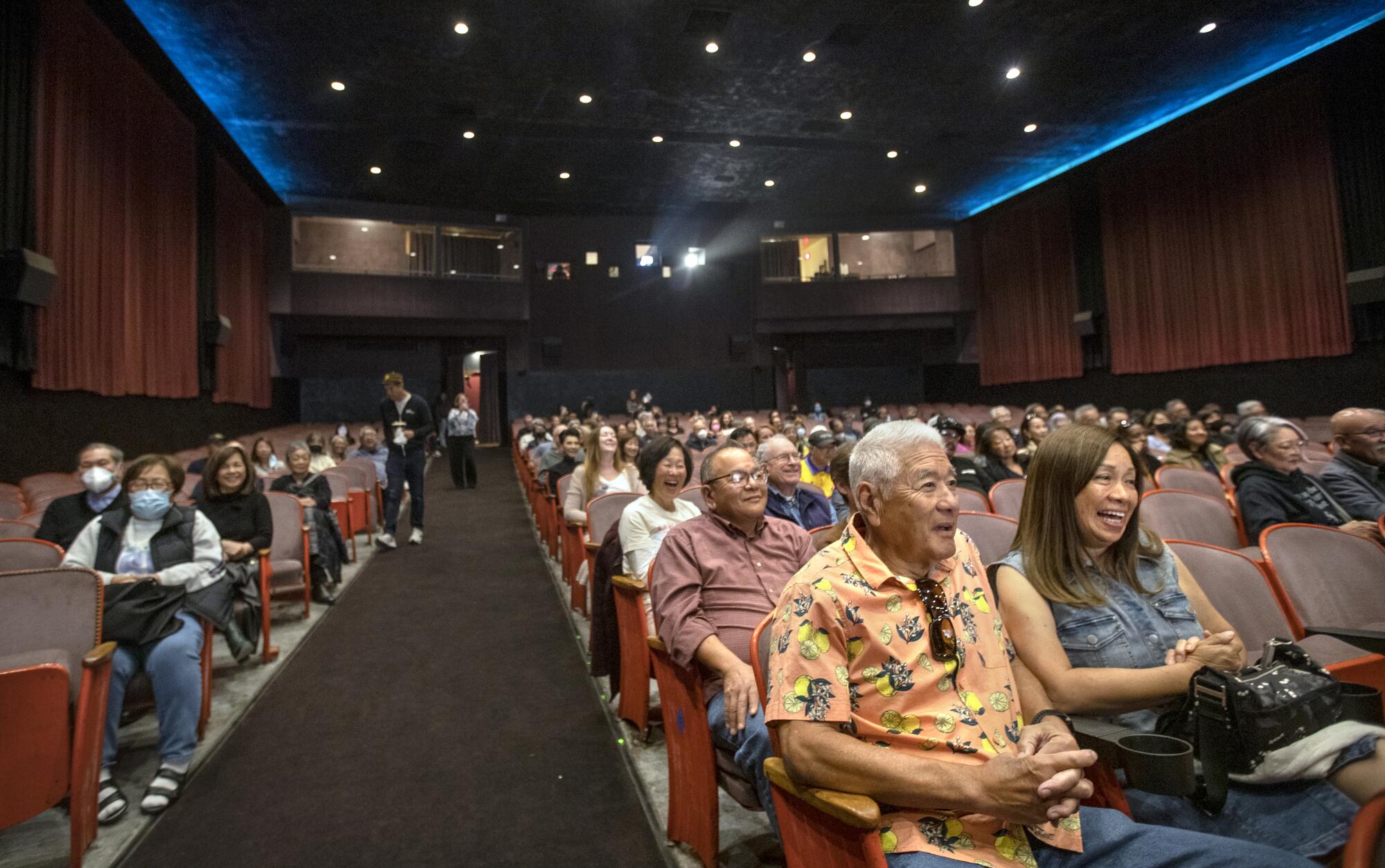 People sit in a large theater all looking up toward a movie screen. 