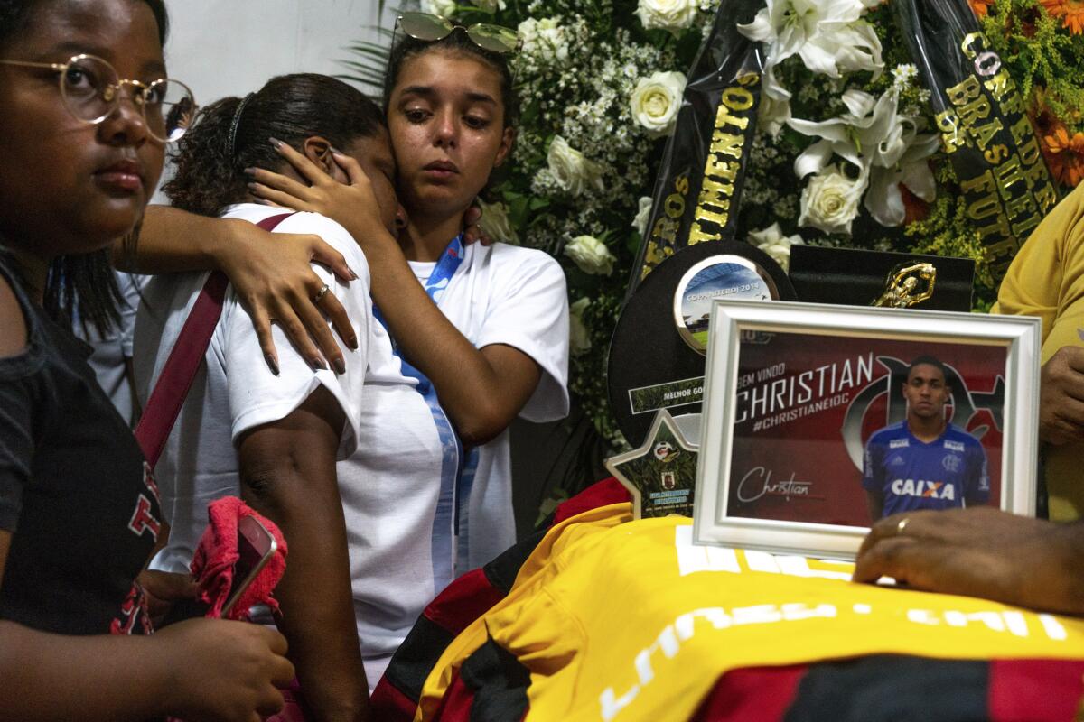 Friends and relatives of the late Christian Esmerio Candido attend his burial at a cemetery in Rio de Janeiro, Brazil, Sunday, Feb. 10, 2019. Hundreds of grief-stricken people attended the funeral of the 15-year-old, one of 10 young soccer players killed in a fire at the training ground of Brazilian soccer club Flamengo on Friday.