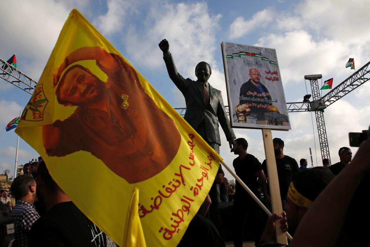 Protesters hold up portraits of Palestinian leader and prominent prisoner Marwan Barghouti in front of a statue of Nelson Mandela in the West Bank city of Ramallah this month.