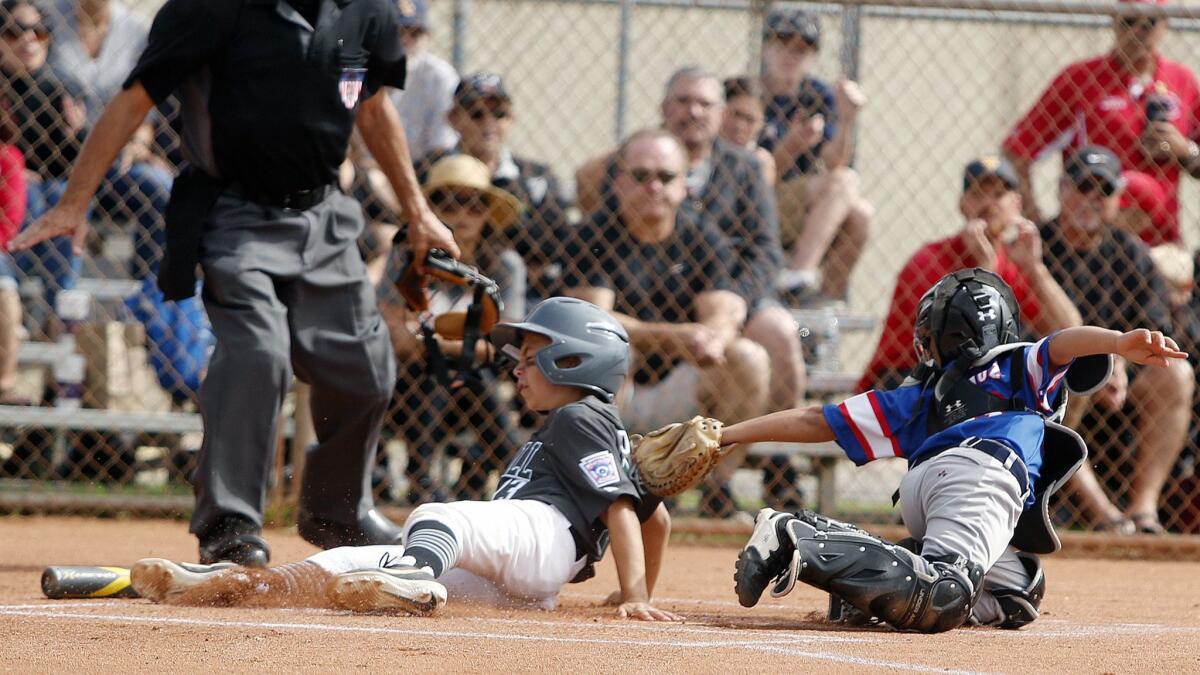 Jude Dravecky slides in safely before the tag catcher Jayden Munoz to score a run for Costa Mesa American in a District 62 All-Star Ocean View Little League baseball game in Huntington Beach on Saturday.