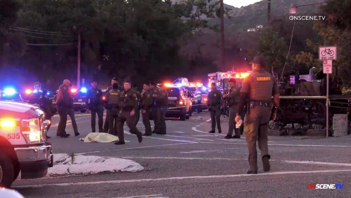 Law enforcement vehicles and officers fill a street.