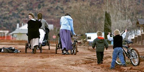 Women wearing the traditional dress favored by polygamist families in the Fundamentalist Church of Jesus Christ of Latter Day Saints walk the dirt roads of Colorado City with their children.